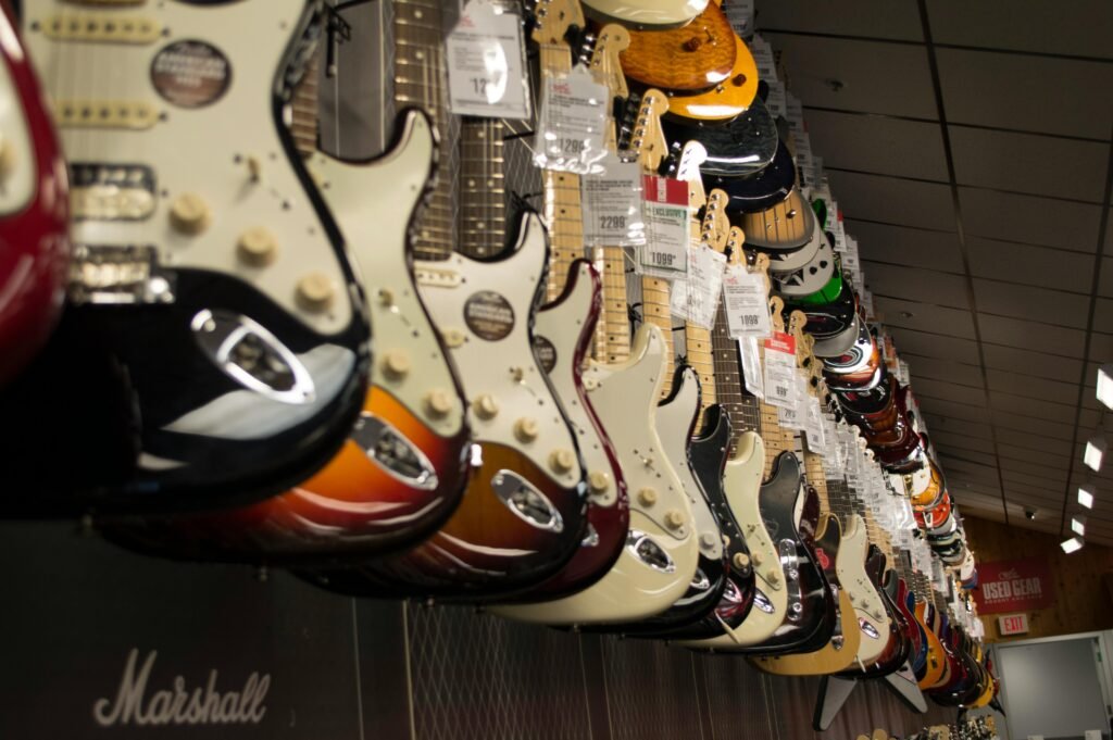 Row of colorful electric guitars hanging in a music store, showcasing diverse models and prices.